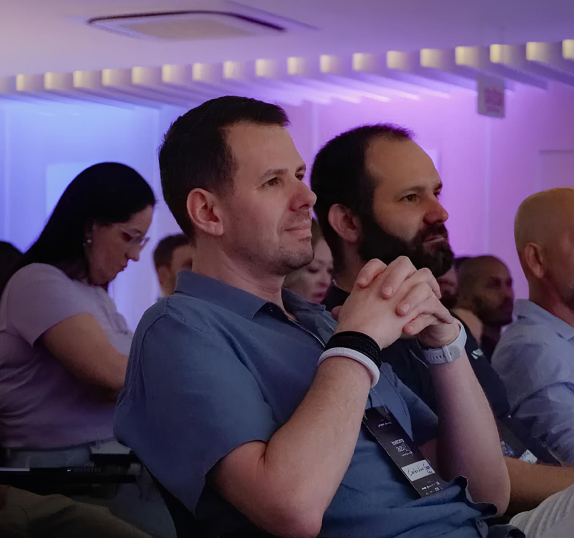 Dois colaboradores da Seprol sentados lado a lado, atentos durante uma apresentação em evento